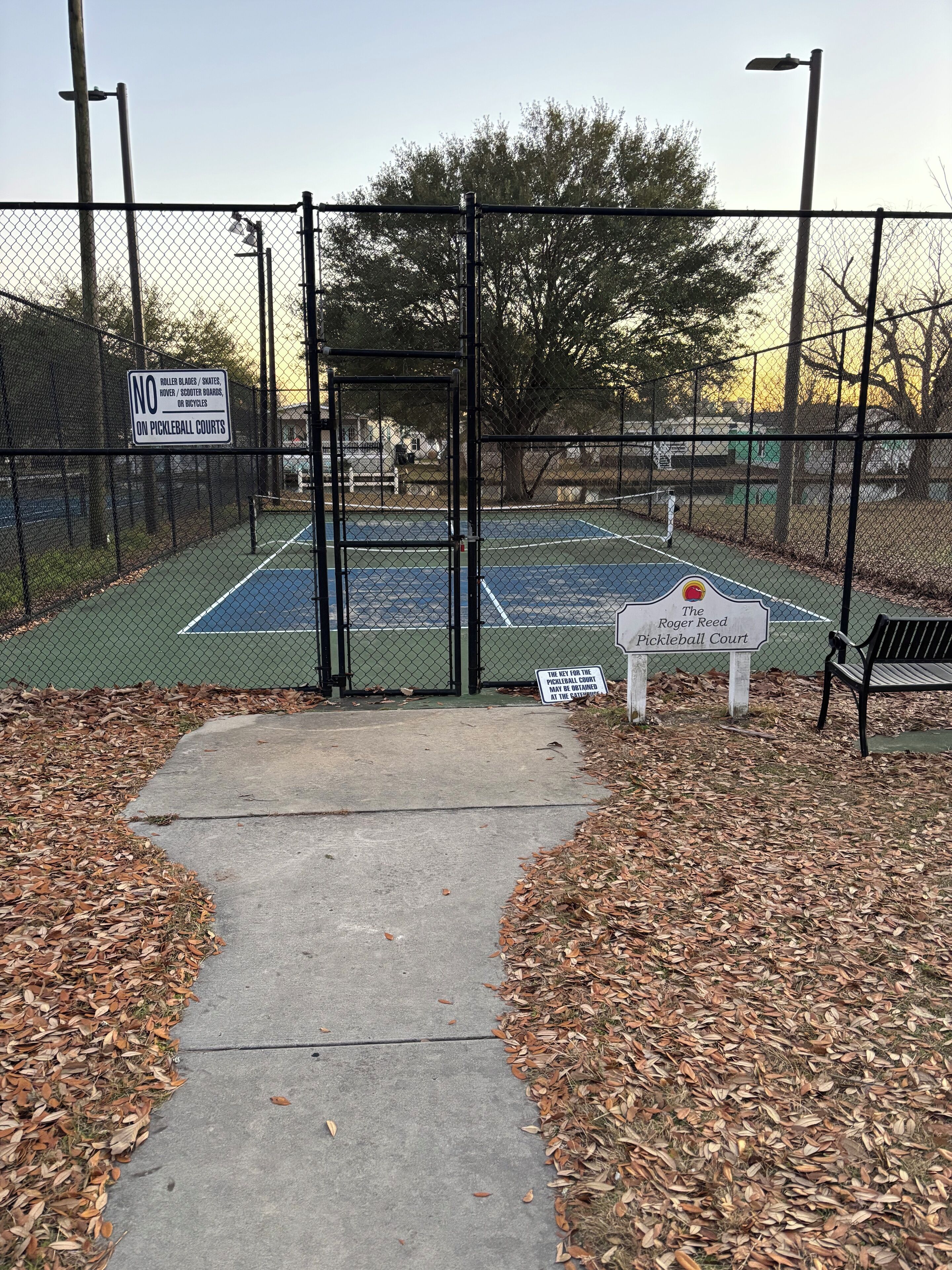 A tennis court with a sign indicating it is The Roger Reed Pickleball Court.