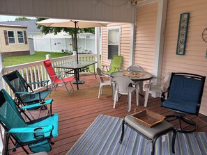 A covered patio with a table and chairs, a wicker basket, and a striped rug. - 3 Bedroom Beach House in Gated Community w/Golf Cart and Private Beach Parking (surfside beach)