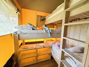 Ein Schlafraum mit Etagenbetten, einem Holztisch und einem Fenster mit Vorhängen.