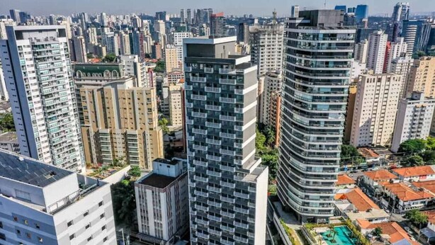 A high-rise building with a modern design, featuring multiple balconies and a rooftop pool area. - Edifício Nex One by Wecare Hosting (São Paulo)