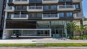 A modern multi-story building with balconies, large glass windows, and a visible entrance. - Edifício Nex One by Wecare Hosting (São Paulo)