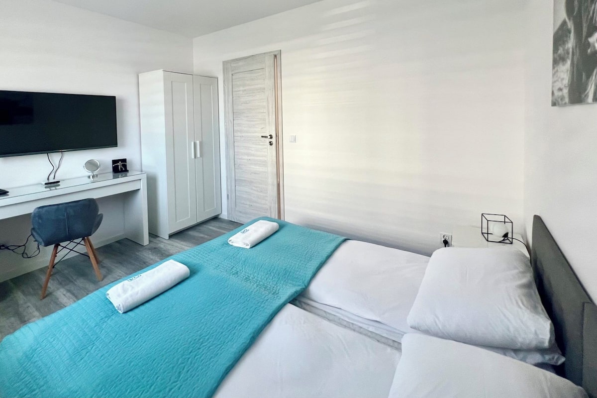 Een moderne hotelkamer met een bed, bureau, televisie en garderobe.