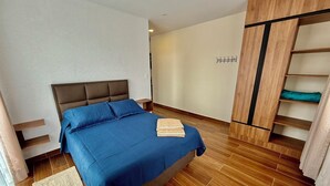 A bedroom with a bed, wooden flooring, a wardrobe, and a wall-mounted coat rack. - Peaceful Apartment in Sucre, steps from the Downtown (Sucre)
