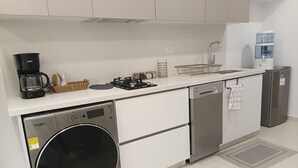 Eine moderne Küche mit Geschirrspüler, Waschmaschine, Kaffeemaschine und Wasserspender.
