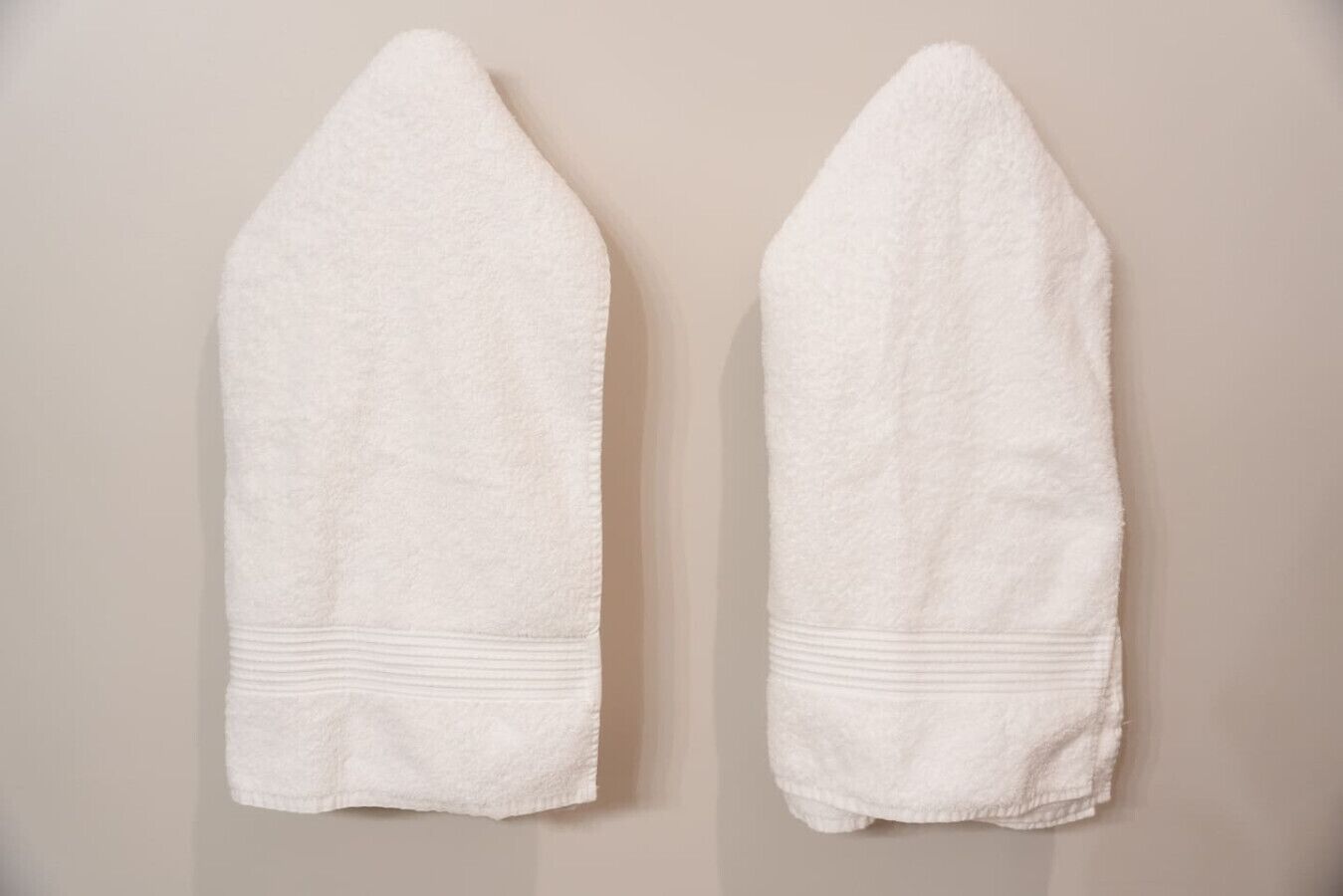 Deux serviettes blanches sont accrochées à un mur.