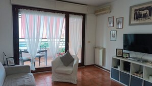 Una sala de estar con un sofá, una silla, un televisor y un radiador.