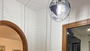 Una habitación con un espejo de marco de madera, una lámpara de techo tipo globo y suelo de baldosas.