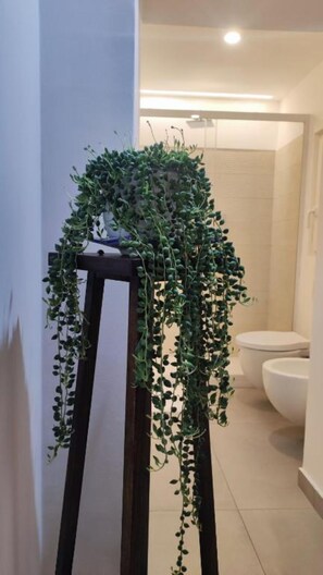 A bathroom with a toilet, a shower area, and a plant on a stand. - Amalo'Guest House romantic loft in Bari Madonella (Bari)
