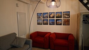 A living room with a grey sofa, a red sofa, and a black lamp. There are nine framed pictures on the wall. - Amalo'Guest House romantic loft in Bari Madonella (Bari)