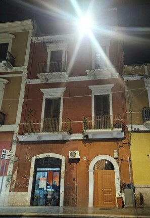 A multi-story building with a ground-level entrance, balconies with railings, and a wooden door. - Amalo'Guest House romantic loft in Bari Madonella (Bari)