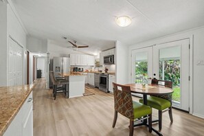 Una cocina moderna con armarios blancos, una isla central y un comedor con una mesa redonda y sillas.