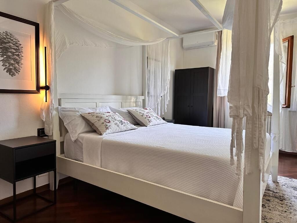 Una cama con dosel, una mesita de noche, un armario oscuro y un cuadro enmarcado en la pared.