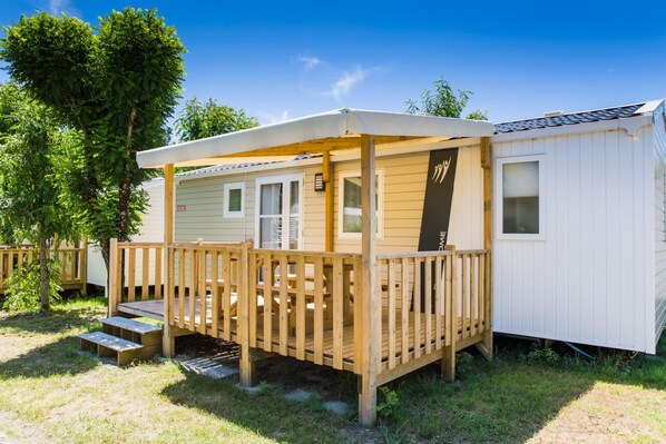 A mobile home with a wooden deck and a covered porch. - Palmyre - Confort 2 - 5p (52) (Les Mathes)