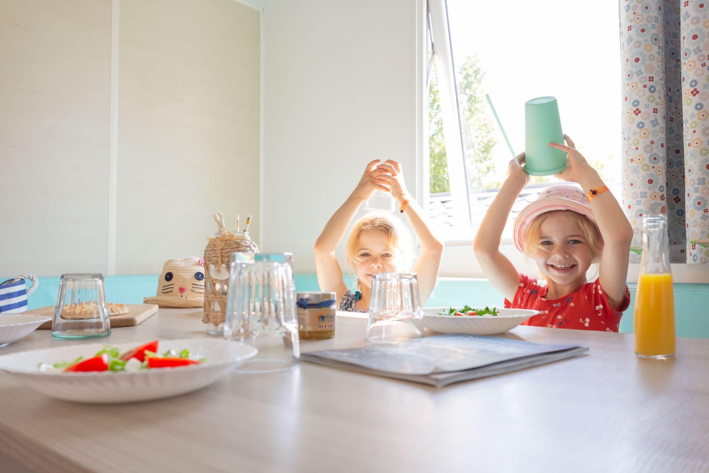 A dining table with plates of food, glasses, and a bottle of juice.