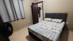 Een slaapkamer met een bed, een kledingkast en een ventilator.
