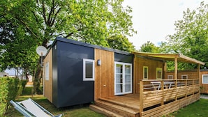 Une petite cabane moderne dotée d’une terrasse en bois et d’un espace salon couvert.
