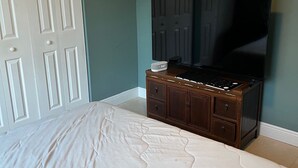 Un dormitorio con una cama grande, un aparador y un televisor en la pared.