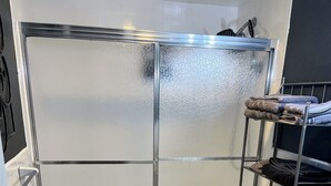 Un baño con cabina de ducha de vidrio, inodoro, lavabo y un perchero para toallas.