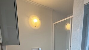 Ein modernes Badezimmer mit einem weißen Waschbecken, einem Spiegel und einer Duschkabine aus Glas.