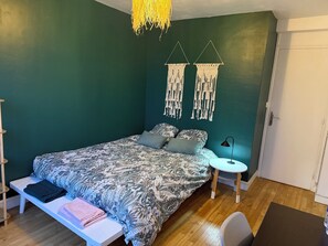 A bedroom with a bed, bedside table, lamp, and macramé wall hangings. - Bright and quiet apartment close to the center of Rennes and the train station. (Rennes)