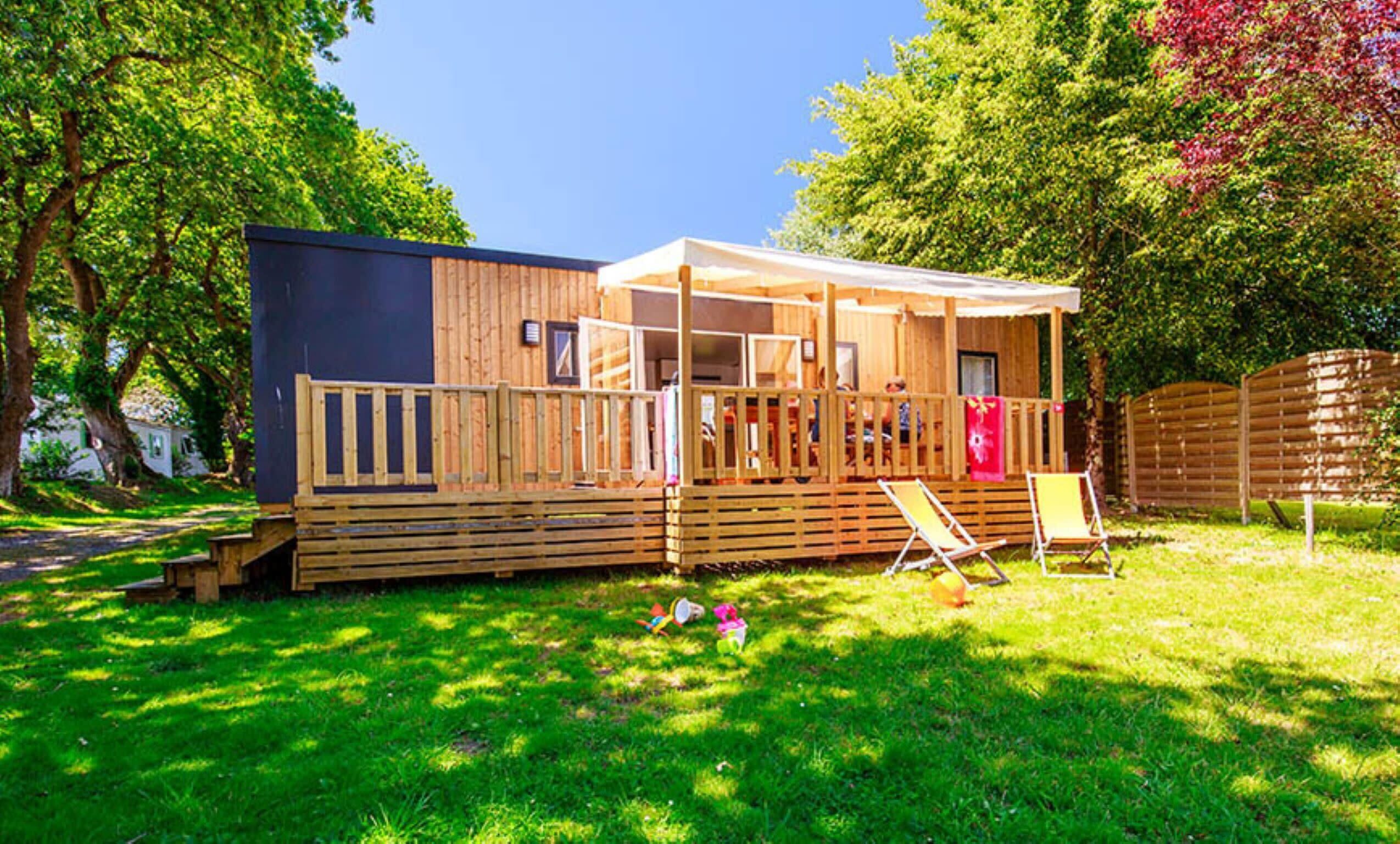 Une cabane en bois dotée d’un porche couvert, d’une terrasse clôturée et d’une cour gazonnée.