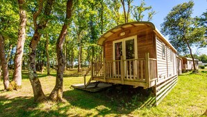 Une cabane en bois avec un porche, entourée d’arbres.