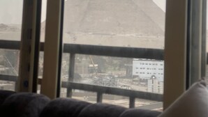 Une vue des pyramides, prise à travers une fenêtre dont le cadre est en métal.