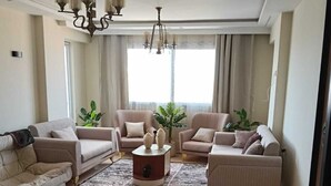 Un salon spacieux agrémenté d’un grand tapis à motifs, de deux canapés, d’une table basse et d’un lustre.