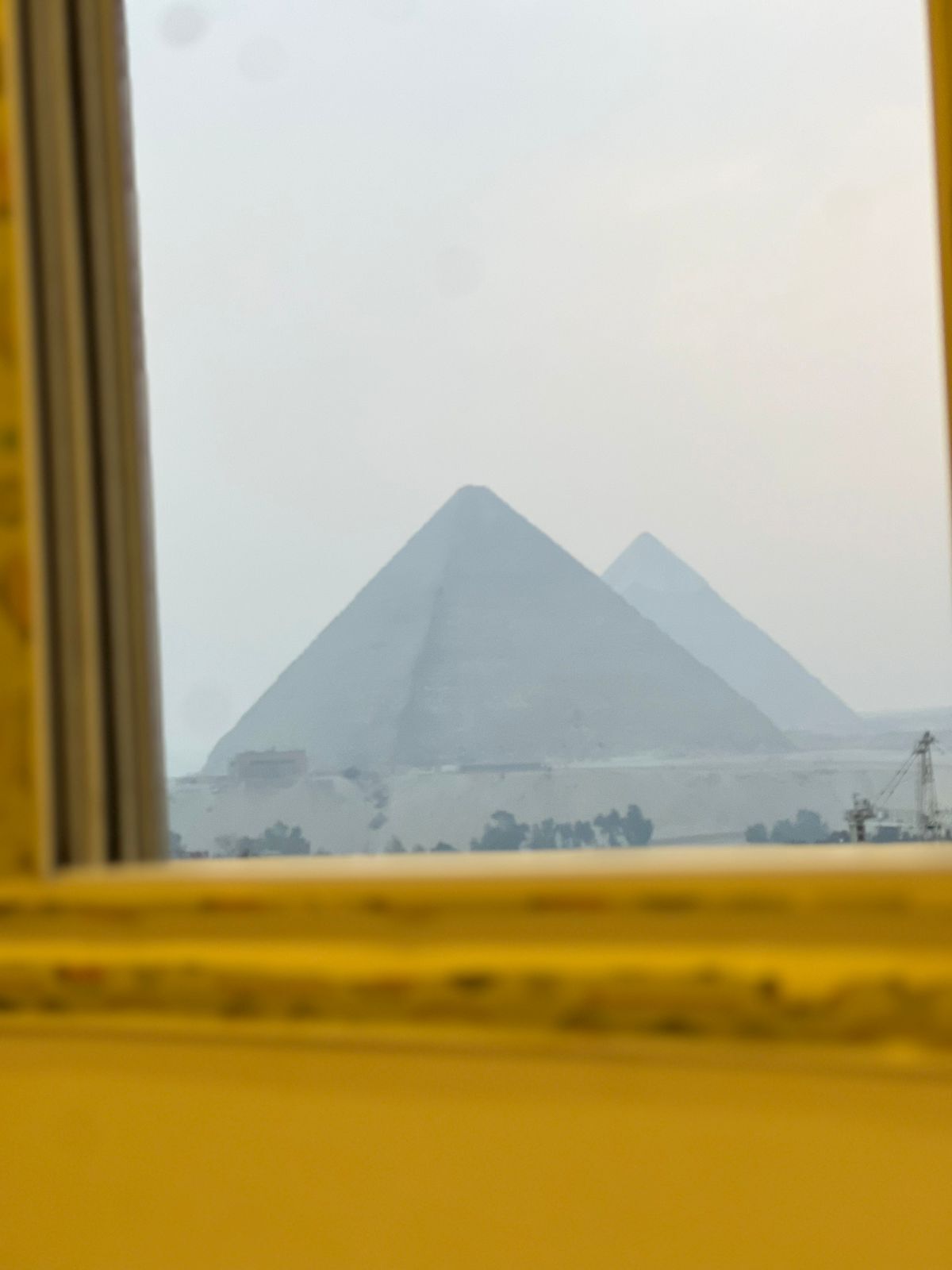 A view of the pyramids through a window with a yellow frame.