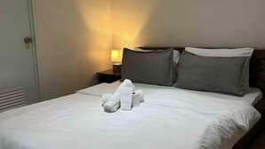 Ein Hotelzimmer mit einem ordentlich bezogenen Bett, einer Nachttischlampe und einer Tür.