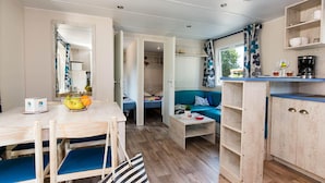 A compact living space with a kitchenette, a dining area, and a sofa. - Bréhadour - Confort 3 TV - 7p (Guérande)