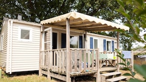A mobile home with a wooden deck and a covered porch. - Bréhadour - Confort 3 TV - 7p (Guérande)