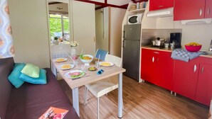 Een kleine keuken met rode kastjes, een magnetron en een koelkast.