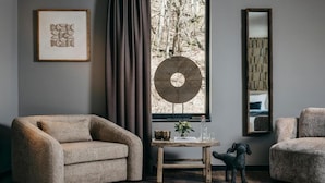 Una habitación con un sofá, una mesita con un florero, un ventilador y un espejo.