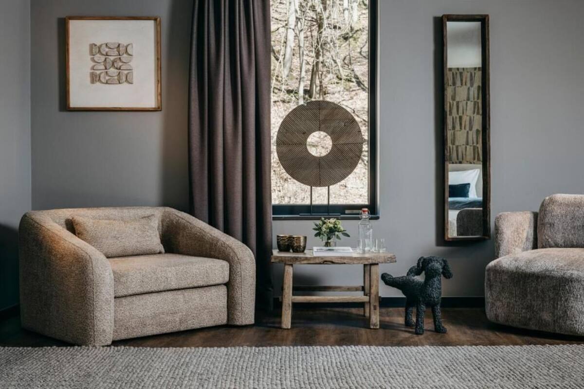 A room with a sofa, a small table with a vase, a fan, and a mirror.