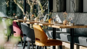 Un restaurante con mesas y sillas de madera, algunas con jarrones y flores.