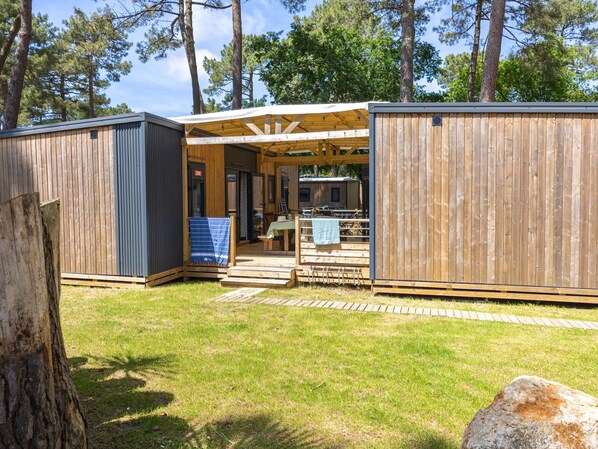 Eine Holzhütte mit offener Veranda, Essbereich und kleiner Küche.