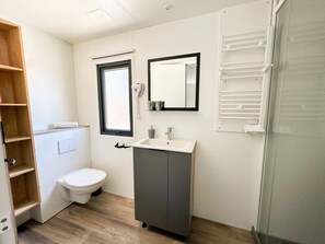 Ein kleines Badezimmer mit Toilette, Waschbecken, Spiegel und Handtuchhalter.