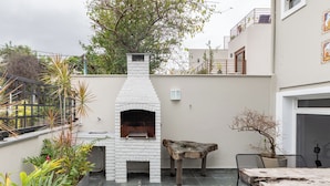 Un patio al aire libre con un horno de ladrillo, una mesa de madera rústica y una zona de estar.