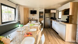 Una cocina moderna con comedor, armarios de madera, microondas integrado y un ventanal grande.