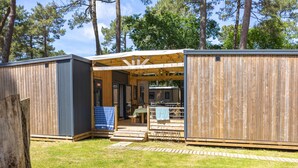 A wooden cabin with an open porch, a dining area, and a small kitchen. - Palmyre - Tribu - 13p (7) (Les Mathes)