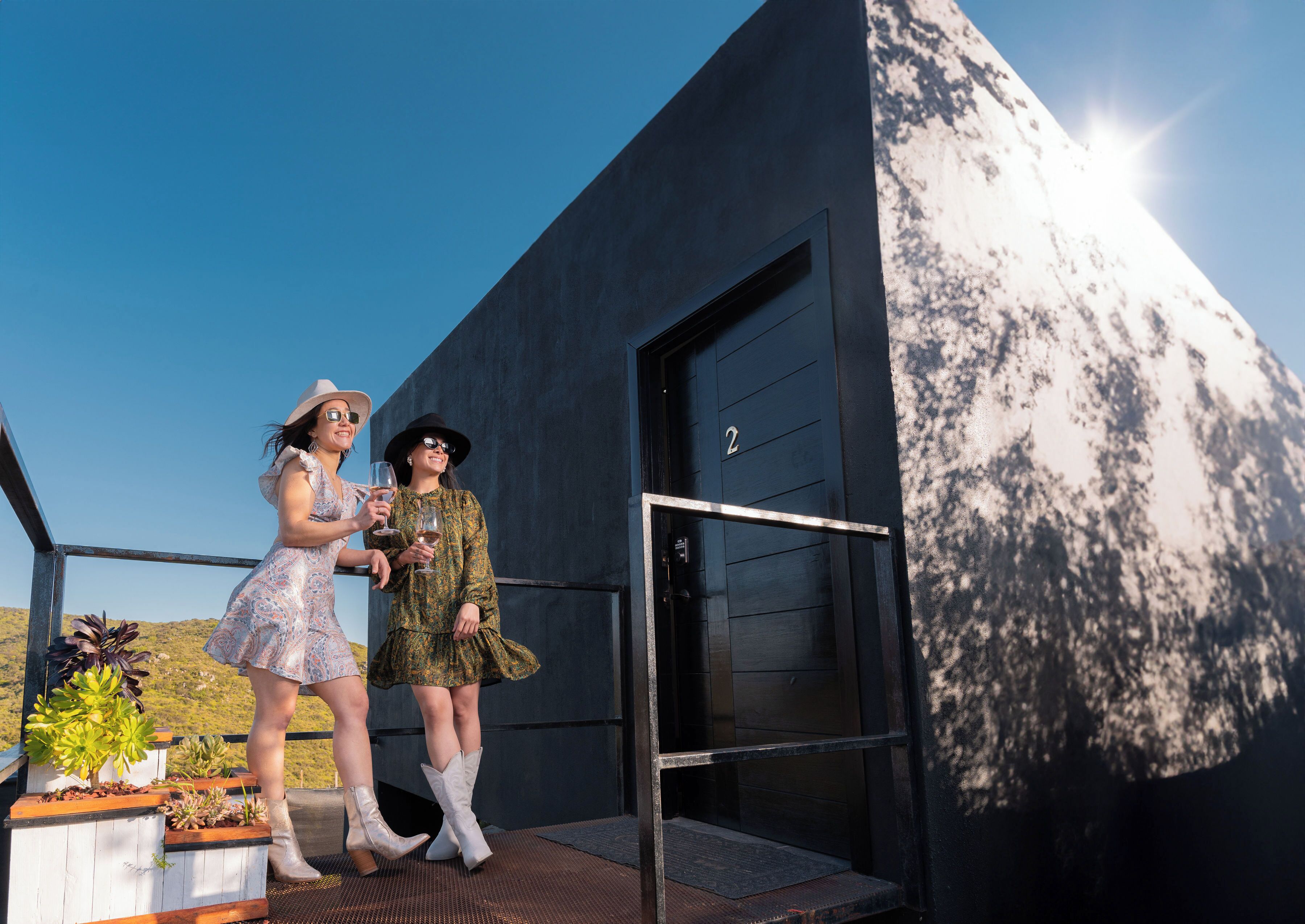 Two people standing on a balcony with a modern building in the background.