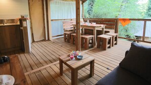 A wooden deck with a table and chairs, a sofa, and a small kitchen area with a sink and cabinets. - Truffe - Eco-lodge 2 – 5p (Saint-Geniès)
