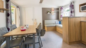 Un espacio habitable compacto y moderno con comedor, rincón de estar y kitchenette.