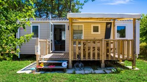 Una casa móvil con terraza, una bicicleta y una pequeña zona de estar al aire libre.