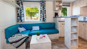 Una cocina moderna con un sofá azul, una cafetera y un ventanal con cortinas.