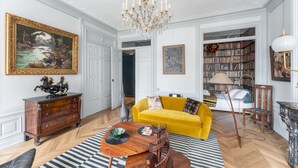 A room with a yellow sofa, a wooden coffee table, a chandelier, a bookshelf, and a large framed painting. - Célestins - Haut standing 120m² - Coeur de Lyon (Lyon)