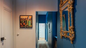 A hallway with a wooden herringbone floor, a patterned rug, a framed picture, and a decorative mirror on a blue wall. - Célestins - Haut standing 120m² - Coeur de Lyon (Lyon)