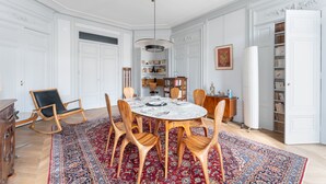 A dining room with a round table, wooden chairs, a patterned rug, and a bookshelf in the background. - Célestins - Haut standing 120m² - Coeur de Lyon (Lyon)