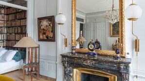 A room with a large bookshelf, a fireplace with decorative items, and a large mirror. - Célestins - Haut standing 120m² - Coeur de Lyon (Lyon)